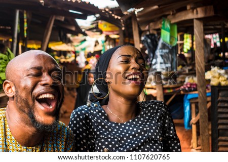 a girl and a guy in a typical african local market laughing  Royalty-Free Stock Photo #1107620765