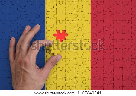 Romania flag  is depicted on a puzzle, which the man's hand completes to fold