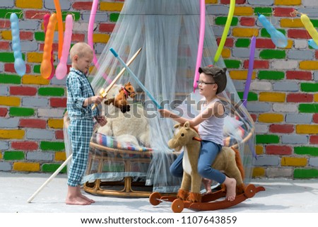 Three boys play superheroes. Military hat with red star, wooden sword, plush toy horses. Bamboo bed with transparent canopy for protection from insects, multicolored brick wall, air balls