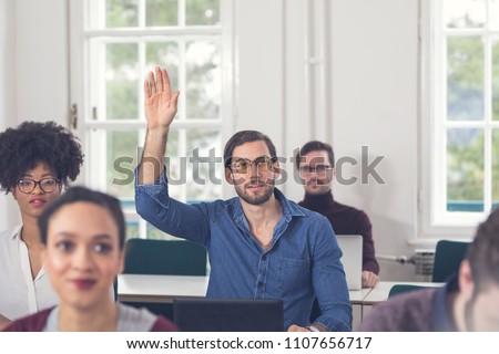 Young Businessman Rasing Hand During Presentation Royalty-Free Stock Photo #1107656717