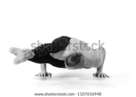 Sporty muscular young yogi man doing handstand, studio shot on white background, front view, full length, black and white