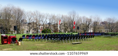  Set up of chairs ready for an official ceremony attending hundreds of peoples, in a park with Canadian flags and speakers, during a beautiful afternoon.                              
