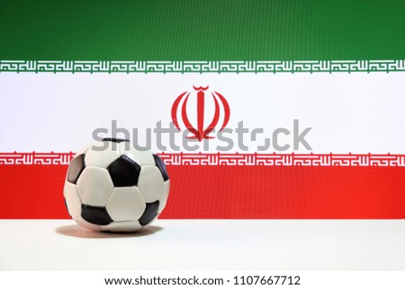 Small football on the white floor and Iran nation flag background. The concept of sport.