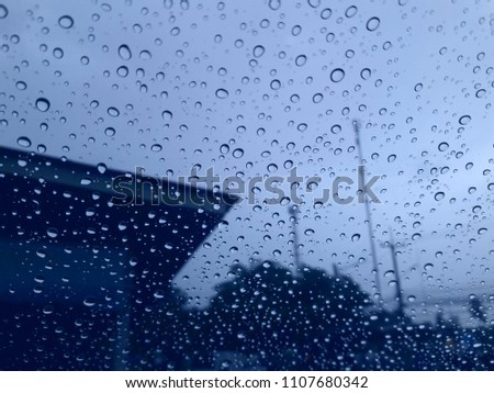 Water drops on glass while the rain is falling with building background. Image with selective focus.
