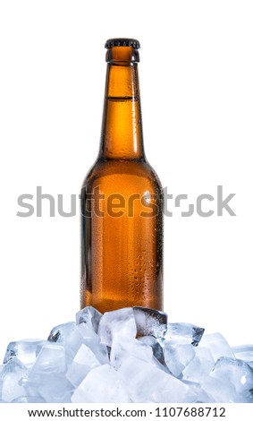 Glass bottle of cold beer in ice on white background
