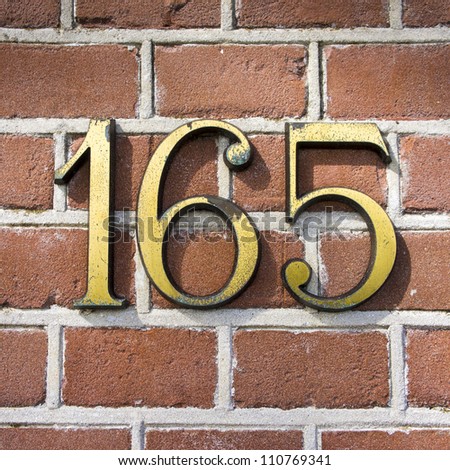 bronze house number one hundred and sixty-five on a red brick wall