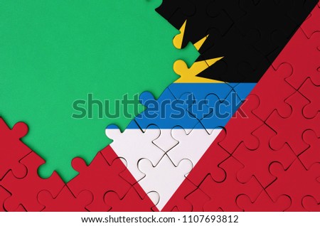 Antigua and Barbuda flag  is depicted on a completed jigsaw puzzle with free green copy space on the left side