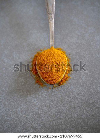 Dry herbs and spices in vintage silver teaspoons. Flat lay of turmeric on gray background.