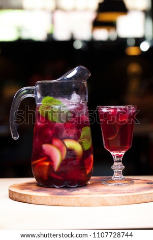 Homemade red wine sangria with orange, apple, strawberry and ice in glass and pitcher