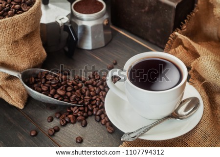 Coffee cup, coffee beans with bag, scoop  and coffee maker pot. dark food photography
