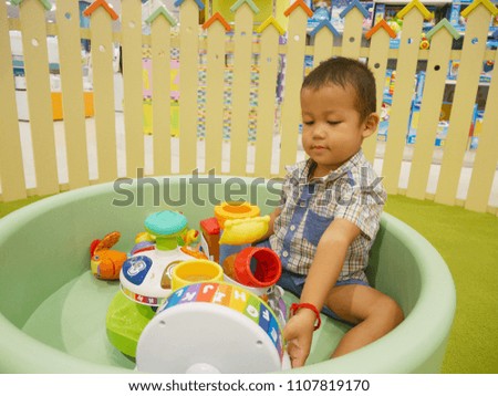A cute Asian boy playing with colorful toys at a department store in Bangkok, kid learning concept