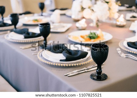 The waiter in uniform with a white towel offers visitors wine in restaurant