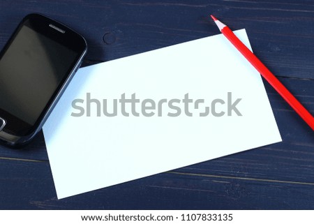 White paper, smartphone and pen on a wooden background
