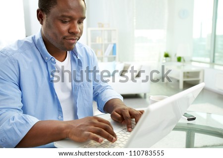 Image of young African man typing on laptop