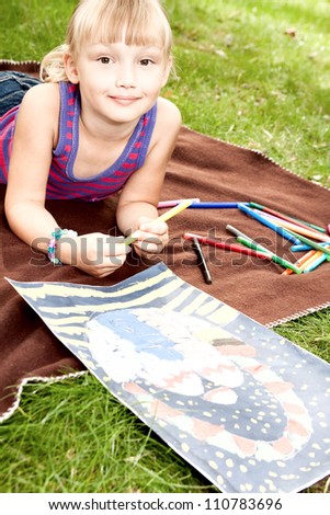 girl lying on the grass draws pictures on the theme of Easter