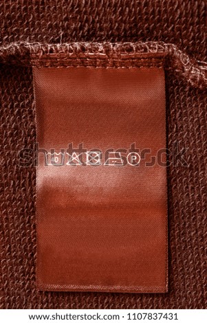 Care clothes label on brown textile background closeup