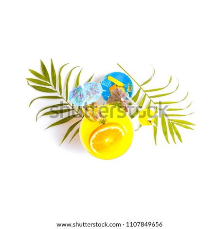 Top view of colorful yellow and blue summer cocktails decorated with tropical fruits, umbrellas and straws on white background with palm tree leaves. Copy space.