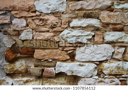 The colorful fragment of the ancient wall in small but beautiful italian town Spello. Different types of stones cemented together in a random order.