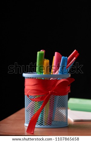 A glass with colored pens on a wooden table. Stationery set. Concept: back to school
