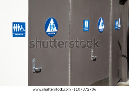 Side view on a row of single occupancy bathroom doors at a public park, with blue and white Handicapped Mens and Womens Restroom signs