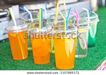 Cold drinks of juice and alcohol in a plastic cup with a tube. Summer holidays and food in nature. Stock Photo