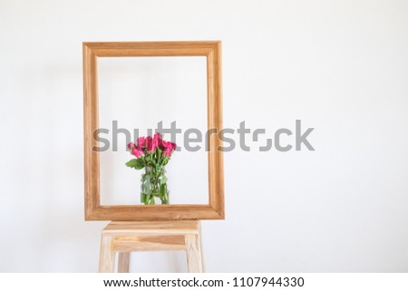 Wooden frame with pink rose bouquet on a chair. Flowers for gift