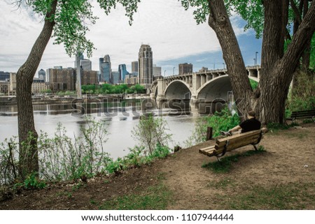 Man on a bench overlooking Minneapolis downtown across the Mississippi River