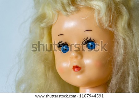 Close-up of beautiful plastic doll with blond hair and blue eyes, sky blue vintage dress and leather shoes. Little princess games.