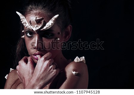 Demon with red skin over black background. Creature from hell, horror concept. Portrait of girl with creative diabolic make-up, Halloween idea.