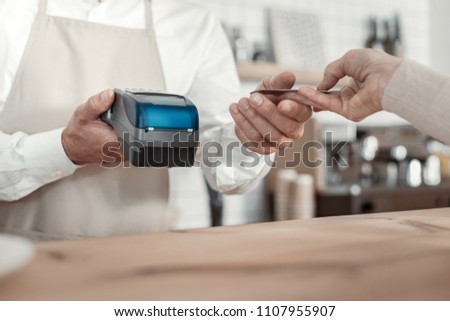 Electronic money. Delighted waiter standing at his workplace while taking payment