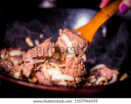 close up wooden stick mixing the meat stew with vegetables with dark background