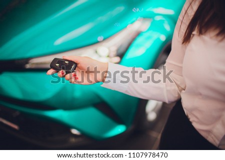 Female holding car keys with car on background beige color
