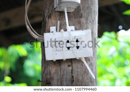 a light switch, a plastic mechanical switch of white color installed on the wooden pole