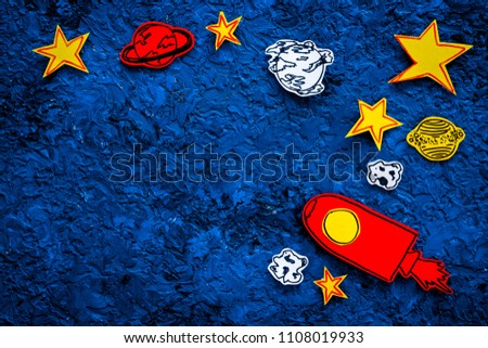 Space tourism concept. Drawn rocket or spaceship near stars, planets, asteroids on blue background top view copy space