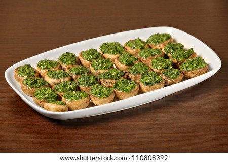 A picture od champignon mushrooms stuffed with spinach and served on a white plate over wooden background