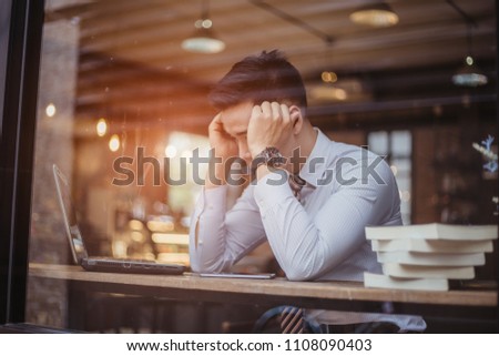 Sad businessman sitting at the table with many folders in office