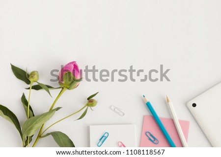 Top view with copy space white table with tablet, white photo frame, clips, pencil and pink peony bud. Summer concept.