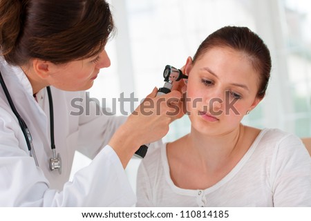 ENT physician looking into patient's ear with an instrument Royalty-Free Stock Photo #110814185