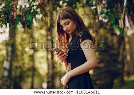 beautiful girl in a black dress walking in the summer sunshine park