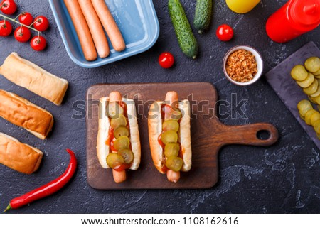 Image on top of two hotdogs on cutting board on table