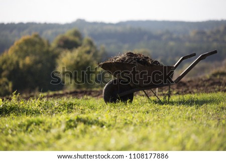 Wheelbarrow with manure on the meadow.