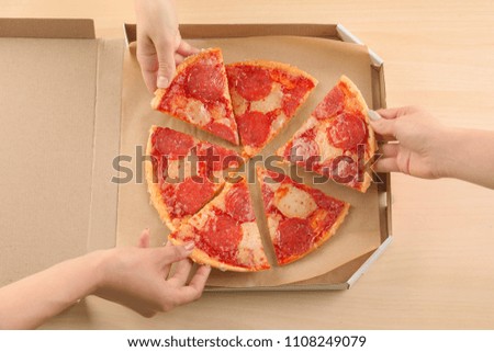 Young women taking pieces of pepperoni pizza from cardboard box