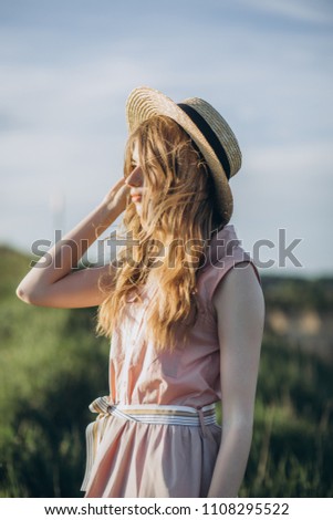 Portrait of young and beautiful blonde girl in hat at mountains. Green gras and beautiful woman