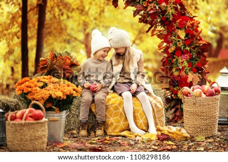 little boy and girl are sitting on haystacks in the autumn landscape Royalty-Free Stock Photo #1108298186
