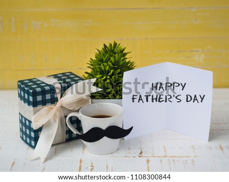 Happy father's day concept. gift box, a cup of coffee with mustache and paper card on white and yellow background.