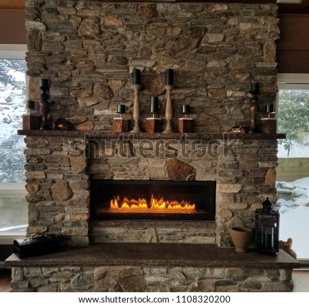 Natural, Rustic, Stone Fireplace With Roaring Flames in Winter Royalty-Free Stock Photo #1108320200