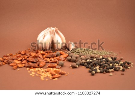 Garlic with spices stock images. Hot peppers and pepper images. Mixture of spices images. Spice mix on a brown background. Aromatic spice collection