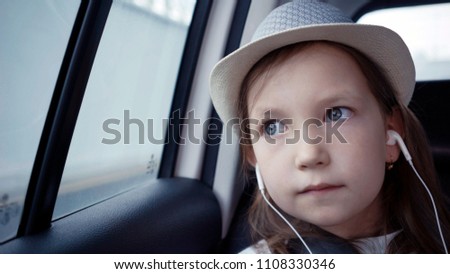 Little girl looking out from car window at sunny day
