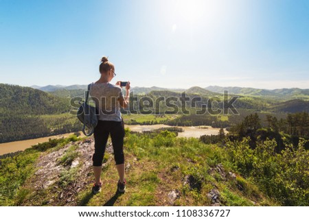 Woman taking photo on mobile phone at the mountain peak.