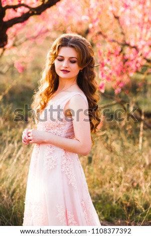 A girl in a beautiful dress strolls through a flowering garden